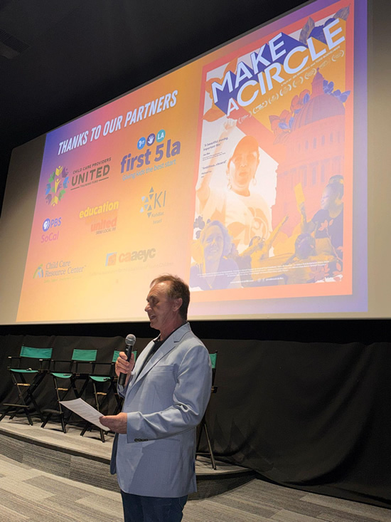 Asm. Zbur onstage, speaking, with large screen display in background