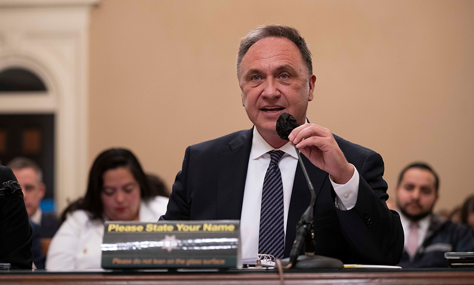 Asm. Zbur seated at table, speaking into microphone