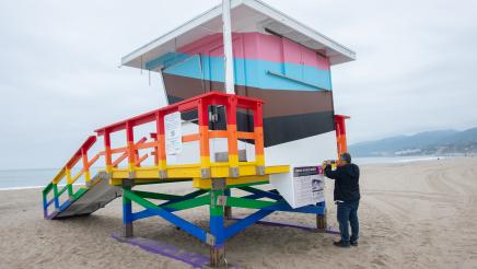 A lifeguard tower on Ginger Rogers Beach dries after being painted in the Progress Pride Flag colors