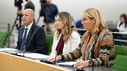 Three witnesses seated, listening on