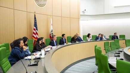 Wide view of select committee members seated at rounded bench