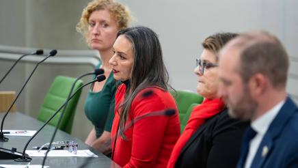 Witness providing testimony as three other witnesses listen on