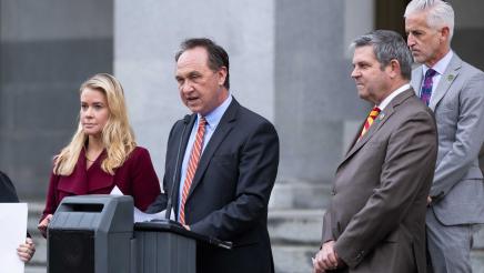 Asm. Zbur at podium, speaking as Asms. Wood and Lowenthal listen on