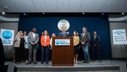 Asm. Zbur at podium, speaking, with other legislators and guests standing in support