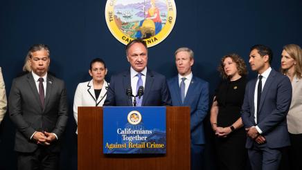 Asm. Zbur at podium, speaking, as Speaker Rivas and other officials listen on