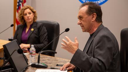 Asm. Zbur speaking and holding one hand up, as Asm. Schiavo listens on