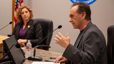 Asm. Zbur speaking and holding one hand up, as Asm. Schiavo listens on