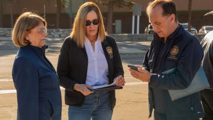 Asm. Zbur conversing with two other members and viewing updates by phone