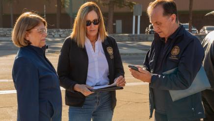 Asm. Zbur conversing with two other members and viewing updates by phone