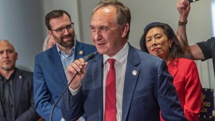 Asm. Zbur, holding microphone and speaking