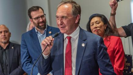 Asm. Zbur, holding microphone and speaking