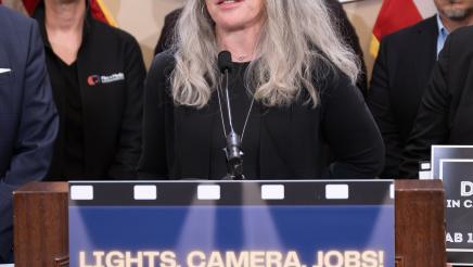 Guest speaker at podium, speaking, with supporters in background